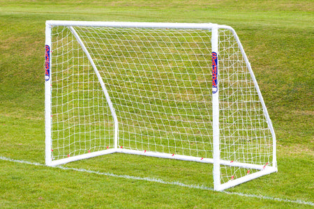 A Samba Sports Match Goal 8 x 6, made from high-impact uPVC with SAMBA branding, stands on a gently sloping grassy field with neatly mown green grass and includes a net.