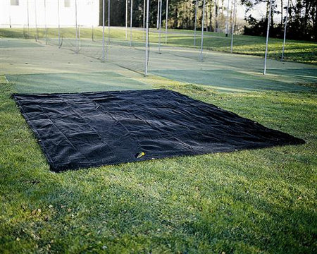 A Martin Berrill Sports Seed Germination Sheet, 4m x 25m in black, is laid flat on grass with sports nets and green turf nearby and trees surrounding the outdoor area.