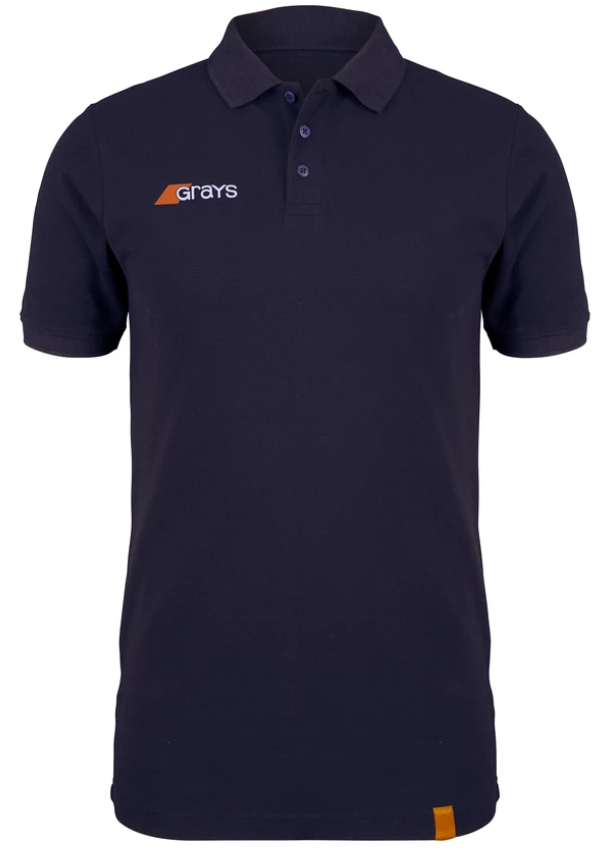 The Grays Junior Tangent Polo Shirt is a navy blue short-sleeve polo with a collar, three buttons, soft pique fabric, a white and orange Grays logo on the left chest, and an orange tag near the bottom hem.