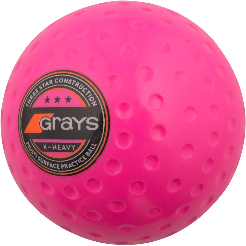 The Grays X-Heavy Hockey Ball is a bright pink, dimpled, heavy practice ball featuring the black and orange Grays logo and "X-Heavy" text—perfect for boosting dribbling and passing strength on any surface.