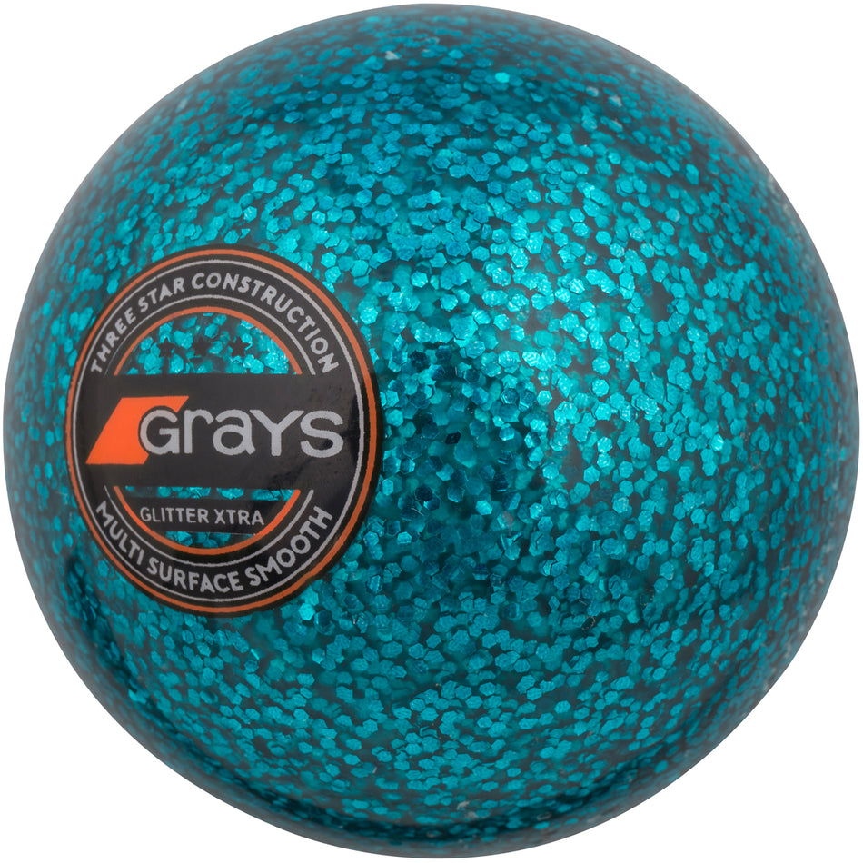 A blue Grays Glitter Xtra Hockey Ball featuring a shiny, textured finish and labeled with "Grays, Three Star Construction, Glitter Xtra, Multi Surface Smooth"—ideal for use under floodlights.