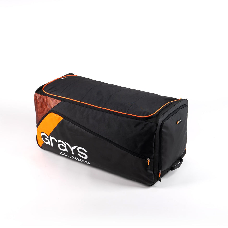 The Grays GK1000 Goalie Holdall is a large black wheelie bag with orange accents, zippered compartments, and "Grays" branding on the side. The bag is shown against a white background.