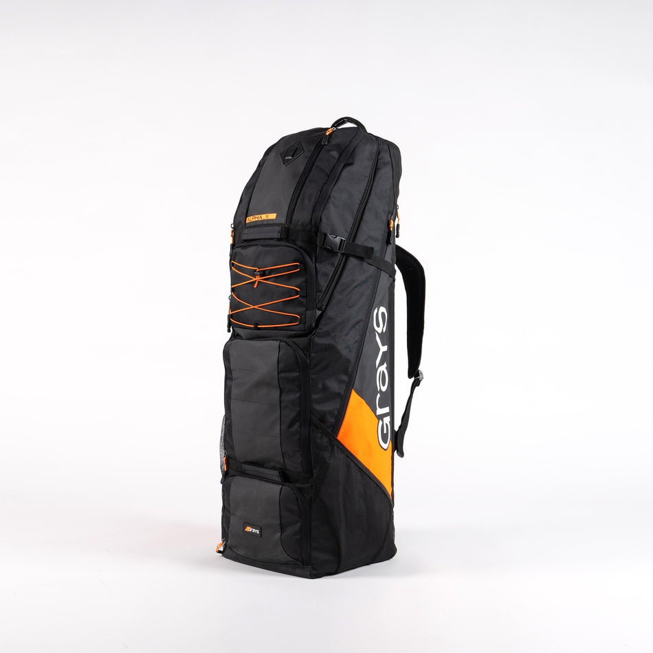 The Grays Alpha-X Kitbag is a tall, black hockey bag with the Grays logo on its side, multiple zippered compartments, a stick pocket, side handle, and adjustable shoulder strap, shown upright on a white background.