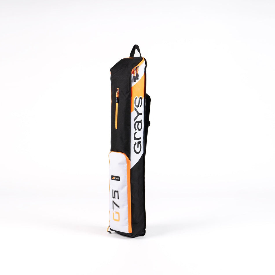 The Grays G75 Stickbag by Grays, in black, white, and orange, stands upright on a white background with a top handle, zipper pockets, water repellent fabric, and the brand logo on the front for secure storage.