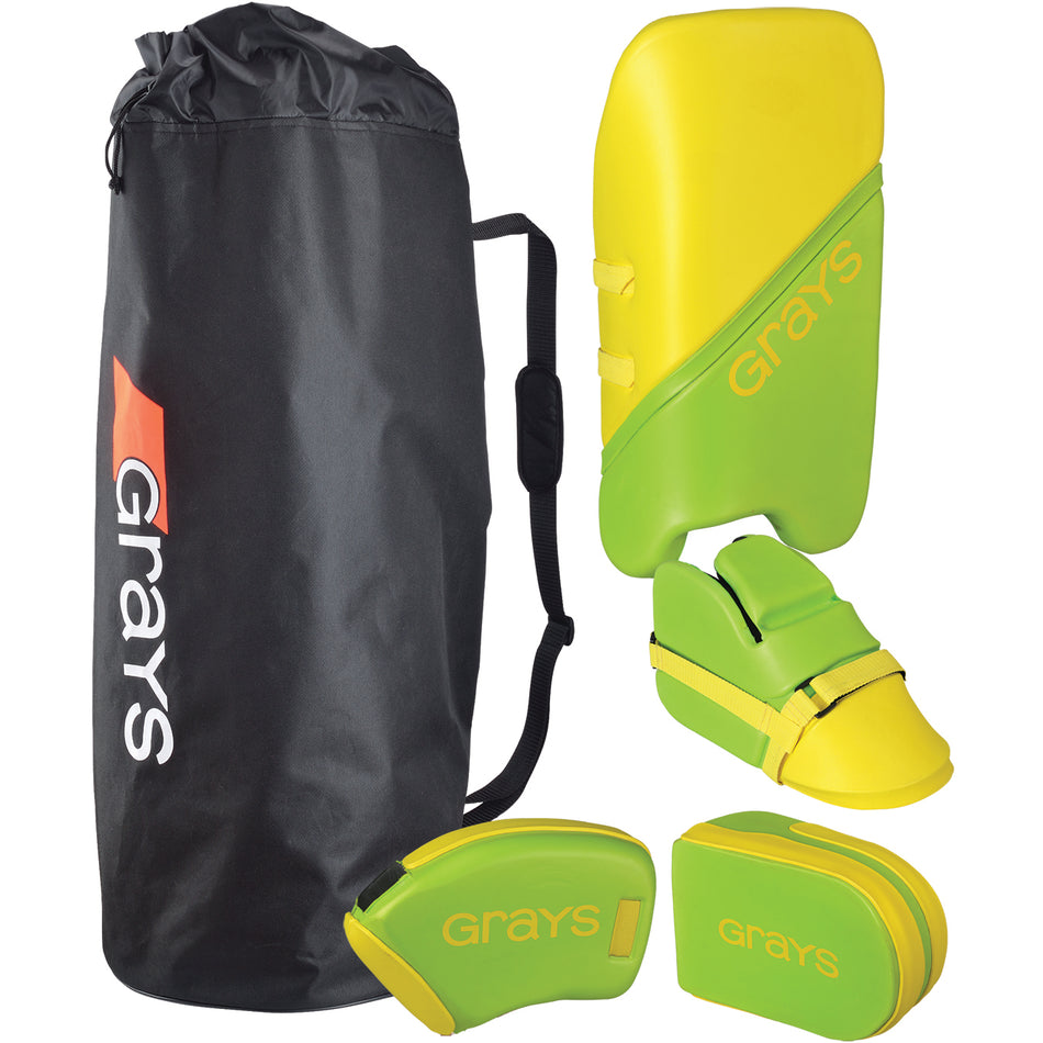 A black Grays sports bag sits next to a Grays G100 Junior Goalie Set in lime/yellow, which includes leg guards, kickers, hand protectors, and a left-hand blocker—all with protective dual-density foam.