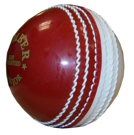A close-up of the Hunts County Bomber Ball by Hunts County in red/white, featuring prominent stitching and part of a gold logo—an ideal choice for cricket training.