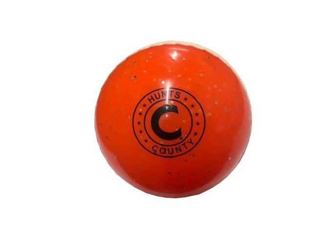 The Hunts County Glitter Ball is an orange PVC training cricket ball with black speckles and logo, shown against a white background.