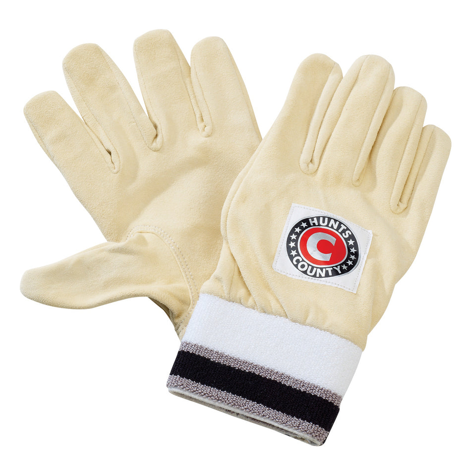 A pair of Hunts County Full Chamois Inners in beige, featuring dark and light striped toweling cuffs and a circular "HUNTS COUNTY" patch on the back of one glove, displayed on a white background.