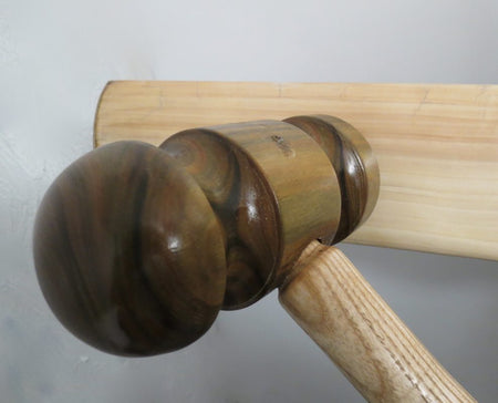 A close-up shows a wooden mallet striking a bat, illustrating the Cricket Bat Knocking In (any Make or Model) service by Martin Berrill Sports—an essential step in professional cricket bat preparation.