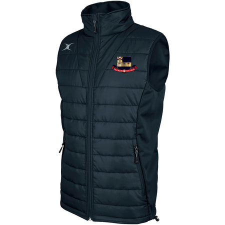 The Gilbert Kings School Pro Body Warmer is a dark blue, sleeveless puffer vest made from breathable technical fabric, featuring a high collar, zip front, two zip side pockets, and an embroidered crest and logo on the chest.