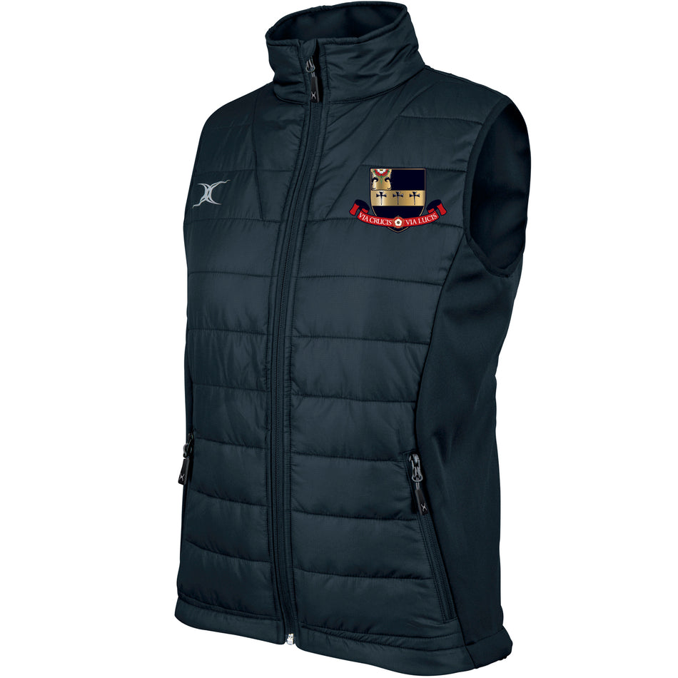 The Kings School Ladies Pro Bodywarmer by Gilbert is black, sleeveless, with a zip-up front, high collar, breathable technical fabric, white Gilbert logo on the right chest, and an embroidered Kings School crest with red banner on the left chest.