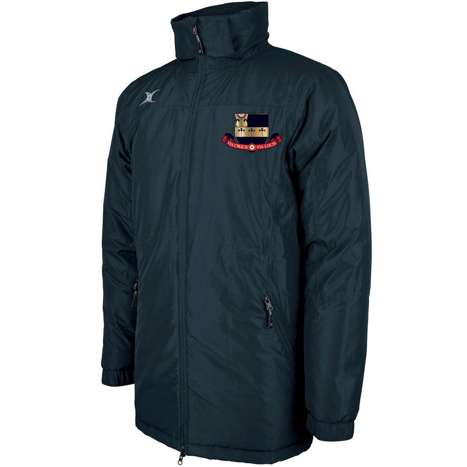 The Gilbert Kings School Pro All-Weather Jacket is dark green with a high collar, zip front, and two zippered side pockets. It features an embroidered shield crest with a red banner on the left chest and a small silver logo on the right shoulder.