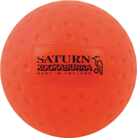 The orange Kookaburra Dimple Saturn Hockey Ball, featuring "SATURN KOOKABURRA MADE IN ENGLAND" and a black bird graphic, is ideal for school hockey or training.