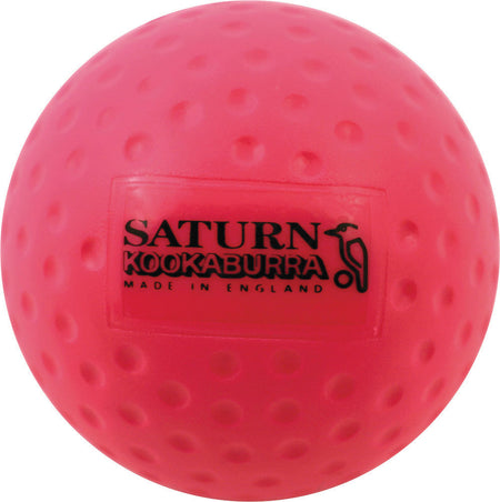 The pink Kookaburra Dimple Saturn Hockey Ball features a black bird logo and SATURN KOOKABURRA MADE IN ENGLAND print—perfect for training or school hockey sessions.
