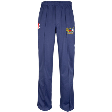 The Gray Nicolls Monmouth CC Matrix V2 T20 Trouser is a navy blue athletic cricket pant with an elastic waistband, loose straight-leg fit, and two embroidered crests on the front thighs—one red and white, one multicolored.