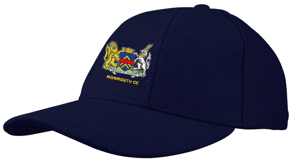 The Gray Nicolls Monmouth CC Melton County Cap is a unisex navy cap with a colorful crest—lion, shield, and unicorn—above embroidered "MONMOUTH CC" and the club’s classic navy logo on the front.