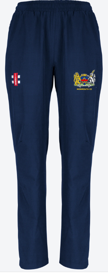 The Monmouth CC Velocity Track Trousers Women's by Gray Nicolls are navy blue with an elastic waistband and two embroidered logos: a red and white flag on the left thigh and a yellow crest with "MONMOUTH CC" on the right.
