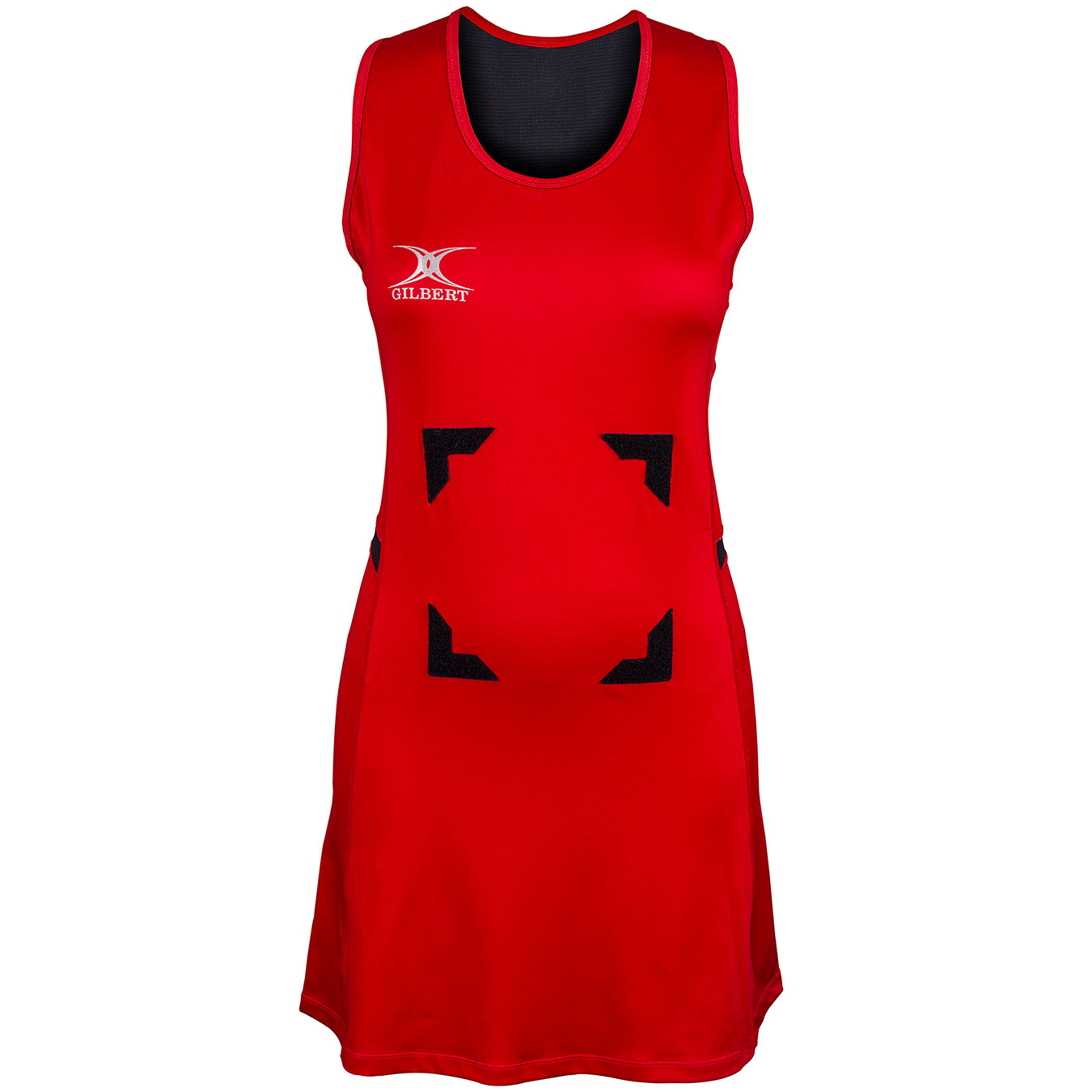 The Gilbert Synergie Netball Dress is a sleeveless red dress featuring black trim at the neckline, a white Gilbert logo on the left chest, and four black rectangular patches arranged in a square on the front.