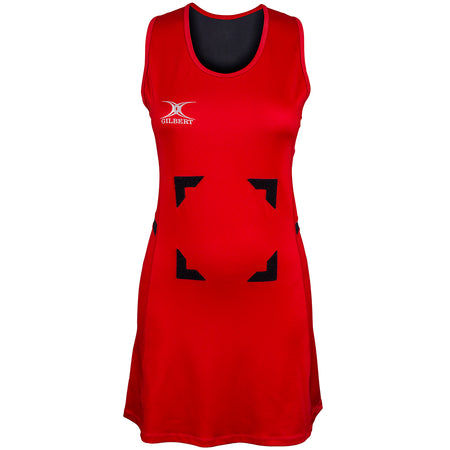 The Gilbert Synergie Netball Dress is a sleeveless red dress featuring black trim at the neckline, a white Gilbert logo on the left chest, and four black rectangular patches arranged in a square on the front.