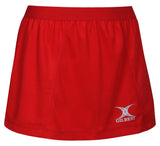 The Gilbert Blaze Netball Skort is a plain red skort with an elasticated waist, moisture-control fabric, and a white Gilbert logo near the bottom right hem.