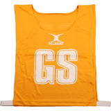 The Gilbert Netball Bibs in amber are made from breathable polyester, featuring "GS" in large white letters on the front with the Gilbert logo above—part of the official Gilbert collection.
