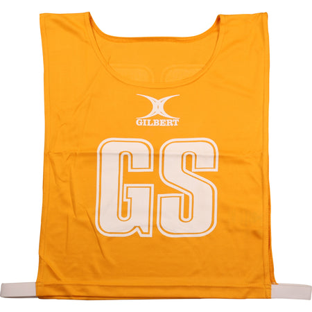 The Gilbert Netball Bibs in amber are made from breathable polyester, featuring "GS" in large white letters on the front with the Gilbert logo above—part of the official Gilbert collection.