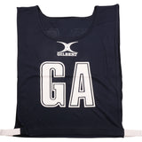 The Gilbert Netball Bibs in navy feature large white GA letters on the front, the Gilbert logo above, and white side straps. Made from breathable polyester for comfort during play.