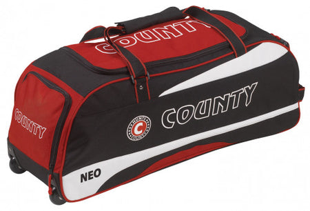 The Hunts County Neo Wheelie Cricket Bag is a red and black holdall with COUNTY on the side, wheels at one end, a top handle, and NEO printed near the bottom—ideal for carrying your cricket gear.
