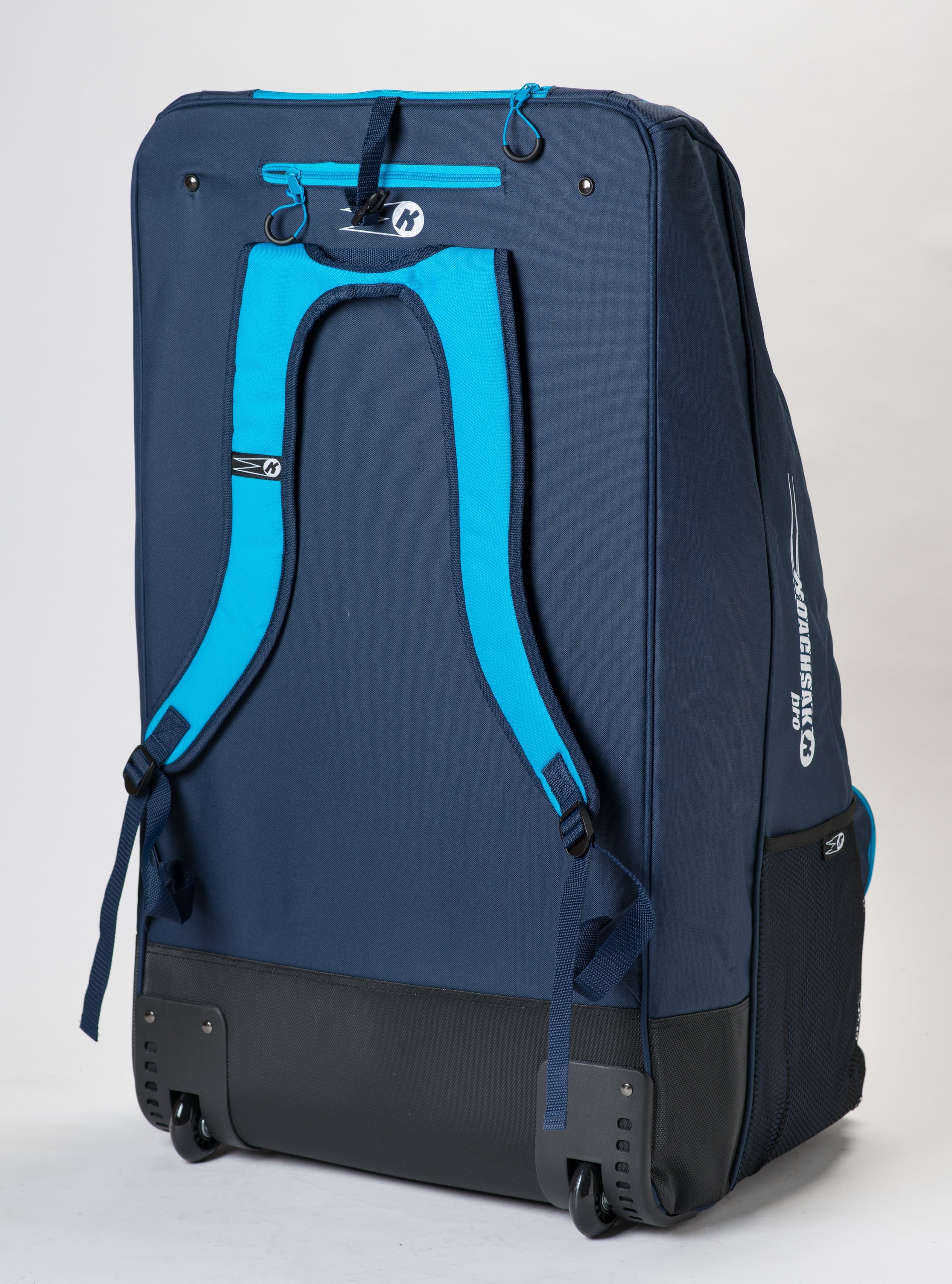 The Katchet KoachSak Pro, a large navy sports bag with bright blue backpack straps, black wheels, and a handle, stands upright against a white background.