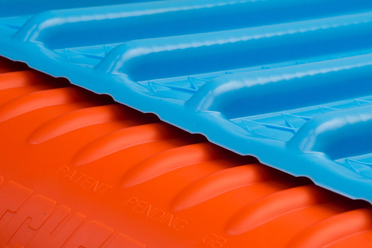 Close-up of a blue ridged plastic sheet overlapping an orange Katchet KatchMax cricket training aid, with "PATENT PENDING" embossed on the orange area.