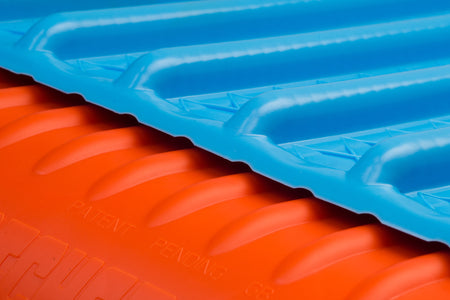 Close-up of a blue ridged plastic sheet overlapping an orange Katchet KatchMax cricket training aid, with "PATENT PENDING" embossed on the orange area.