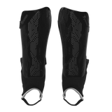 The Precision Training Precision Origin.0 Shin & Ankle Guards in Black/Black feature geometric patterns and black fabric sleeves with white elastic foot loops for football protection, shown on a white background.
