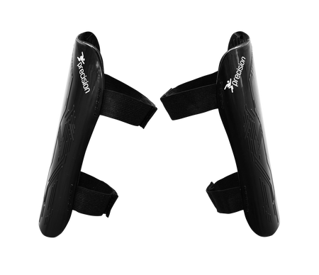 A pair of black Precision Training Origin.0 Strap Shin Guards with adjustable Velcro straps are placed facing each other on a white background. Each lightweight guard displays the Precision logo and offers high impact protection.