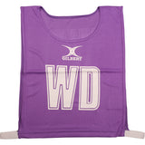 The Gilbert Netball Bibs by Gilbert in purple feature "WD" in bold white letters, made from breathable polyester for comfort—ideal for Wing Defence and perfect as part of a netball bibs set.