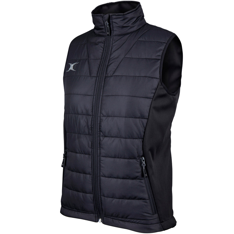The Gilbert Pro Womens Bodywarmer by Gilbert is a black, water-repellent, sleeveless quilted vest featuring a front zipper, zippered side pockets, high collar, and a small white logo on the upper left chest.
