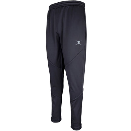 The Gilbert Pro Warm Up Trouser by Gilbert features a slim fit in black, made from water-repellent technical fabric with an elastic waistband and small gray logo on the left thigh. Visible leg stitching shown against a white background.