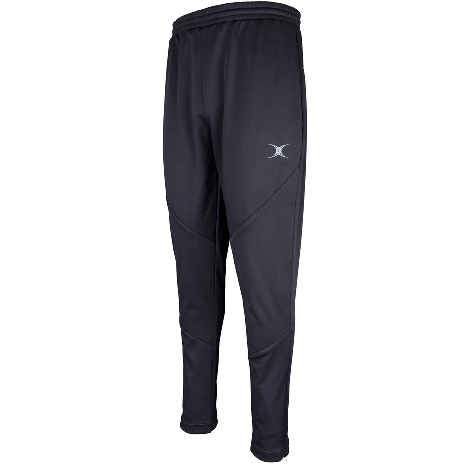 The Gilbert Pro Warm Up Trouser by Gilbert features a slim fit in black, made from water-repellent technical fabric with an elastic waistband and small gray logo on the left thigh. Visible leg stitching shown against a white background.