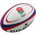 The Gilbert England Replica Rugby Ball is a white ball with red and blue accents, featuring the iconic red rose emblem, "England Rugby" text, and Gilbert logo—ideal for fans and Rugby World Cup 2023 supporters.