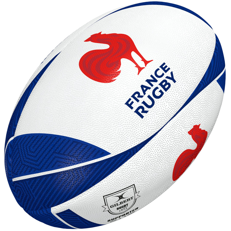 The Gilbert France Supporter Rugby Ball by Gilbert is white and blue with a red rooster logo, "FRANCE RUGBY" text, Rugby World Cup branding, Gilbert logo, and textured patterns.