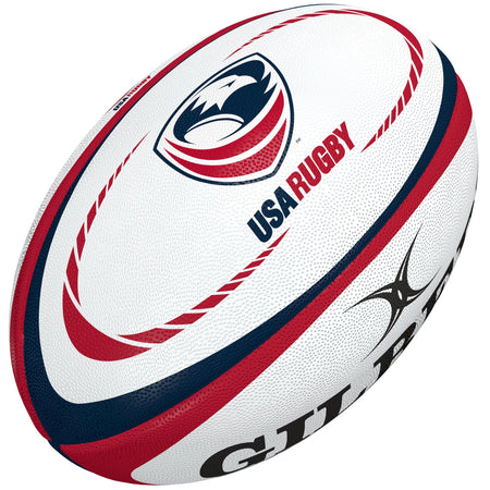 The Gilbert USA Replica Rugby Ball features red and blue curved stripes, the USA Rugby logo, and a partial black Gilbert brand logo—a perfect gift for rugby fans or collectors.
