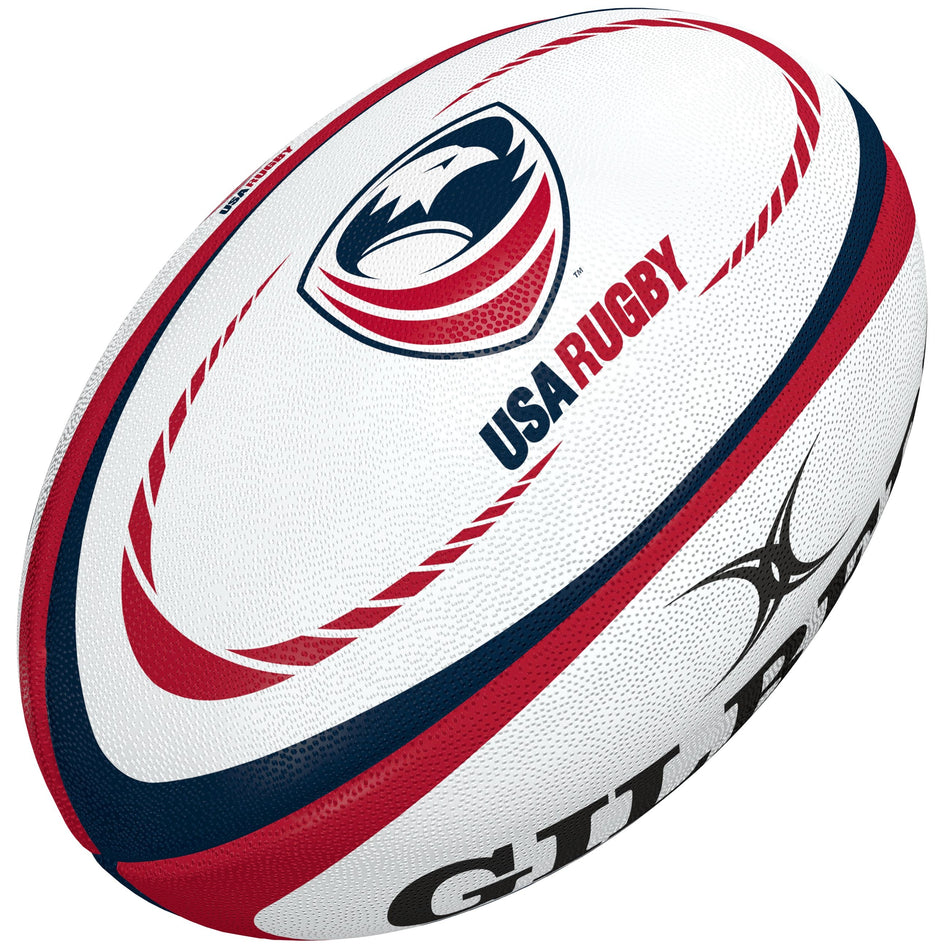 The Gilbert USA Replica Rugby Ball features red and blue curved stripes, the USA Rugby logo, and a partial black Gilbert brand logo—a perfect gift for rugby fans or collectors.