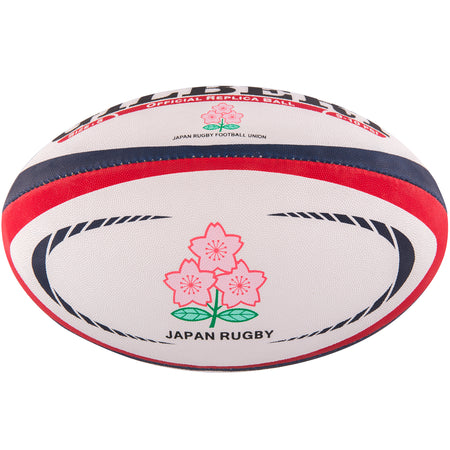 The Gilbert Japan Replica Rugby Ball by Gilbert is white with red and blue stripes, features two pink Cherry Blossoms with green stems, and has "JAPAN RUGBY" printed below the flowers.