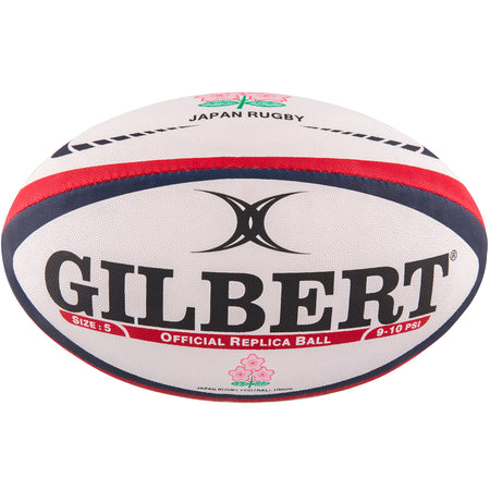 The Gilbert Japan Replica Rugby Ball by Gilbert is white with red and blue stripes, bold GILBERT text, a cherry blossom JAPAN RUGBY emblem, and "Official Replica Ball" printed on it.