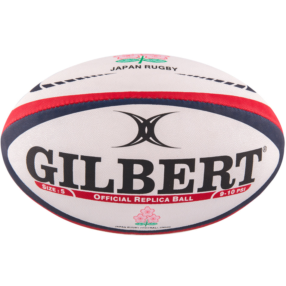 The Gilbert Japan Replica Rugby Ball by Gilbert is white with red and blue stripes, bold GILBERT text, a cherry blossom JAPAN RUGBY emblem, and "Official Replica Ball" printed on it.