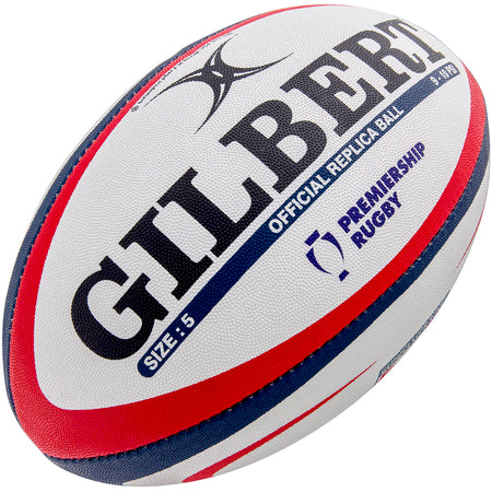 The Gilbert Gloucester Replica Rugby Ball is white with red and blue stripes, features the Premiership Rugby logo, Gloucester Rugby branding, and bold black “GILBERT” text. “OFFICIAL REPLICA BALL” and “SIZE: 5” are also printed on the ball.