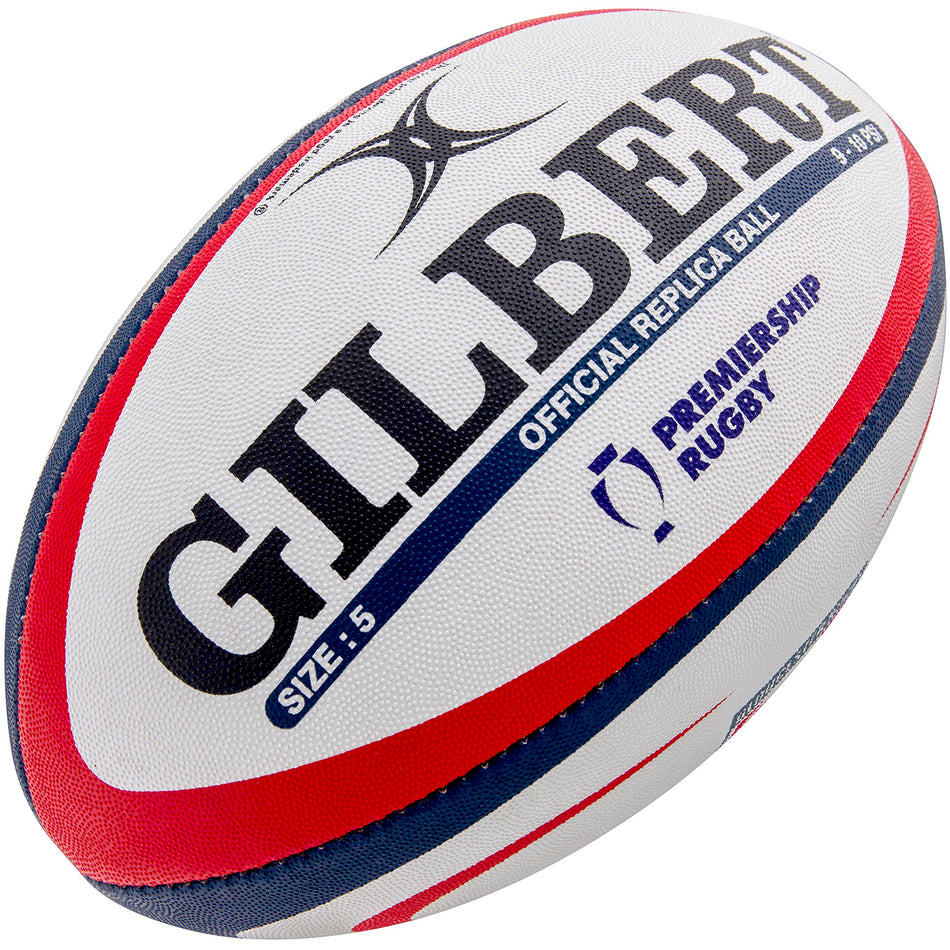 The Gilbert Gloucester Replica Rugby Ball is white with red and blue stripes, features the Premiership Rugby logo, Gloucester Rugby branding, and bold black “GILBERT” text. “OFFICIAL REPLICA BALL” and “SIZE: 5” are also printed on the ball.