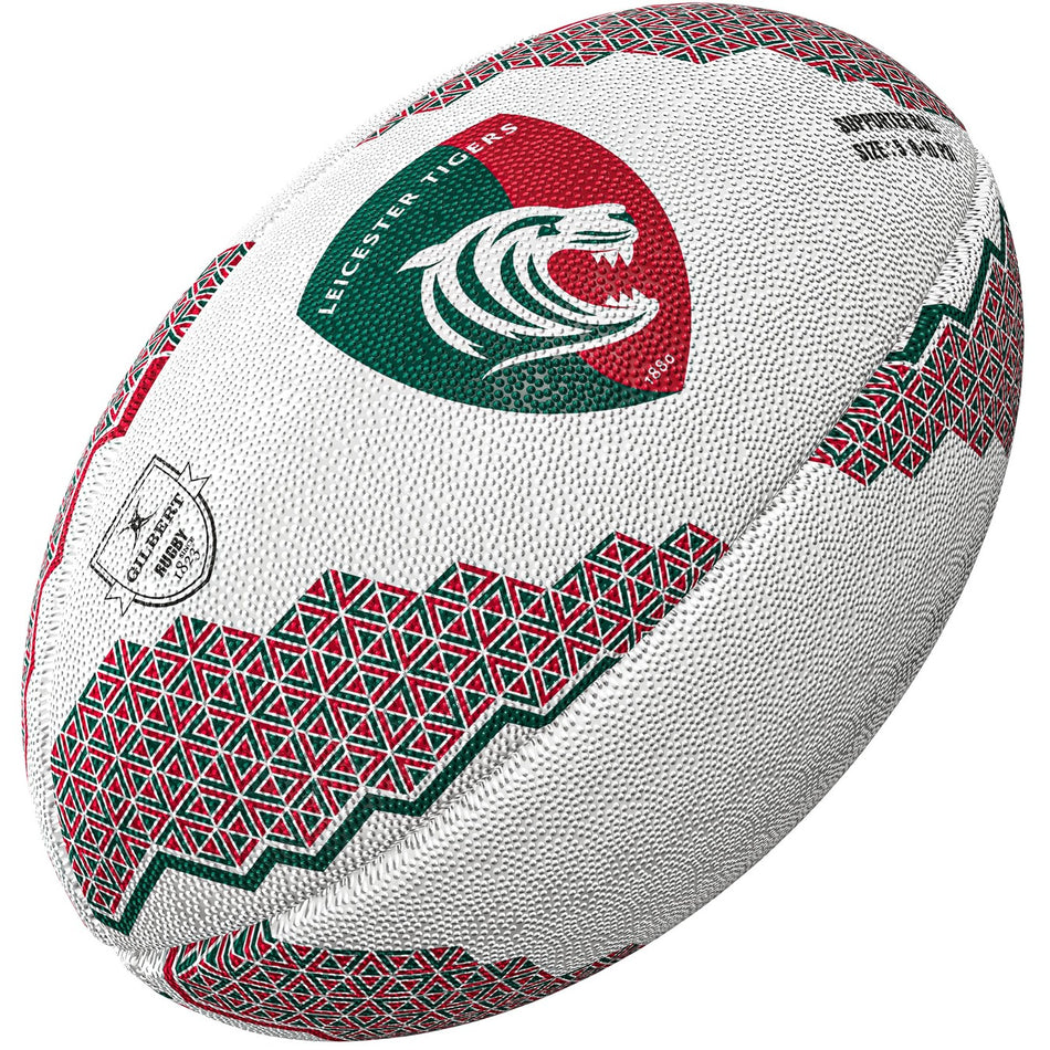 The Gilbert Leicester Tigers Supporter Rugby Ball by Gilbert features white panels with green and red geometric patterns and the Tigers’ roaring tiger head logo in a shield, making it ideal for any Premiership Rugby fan.