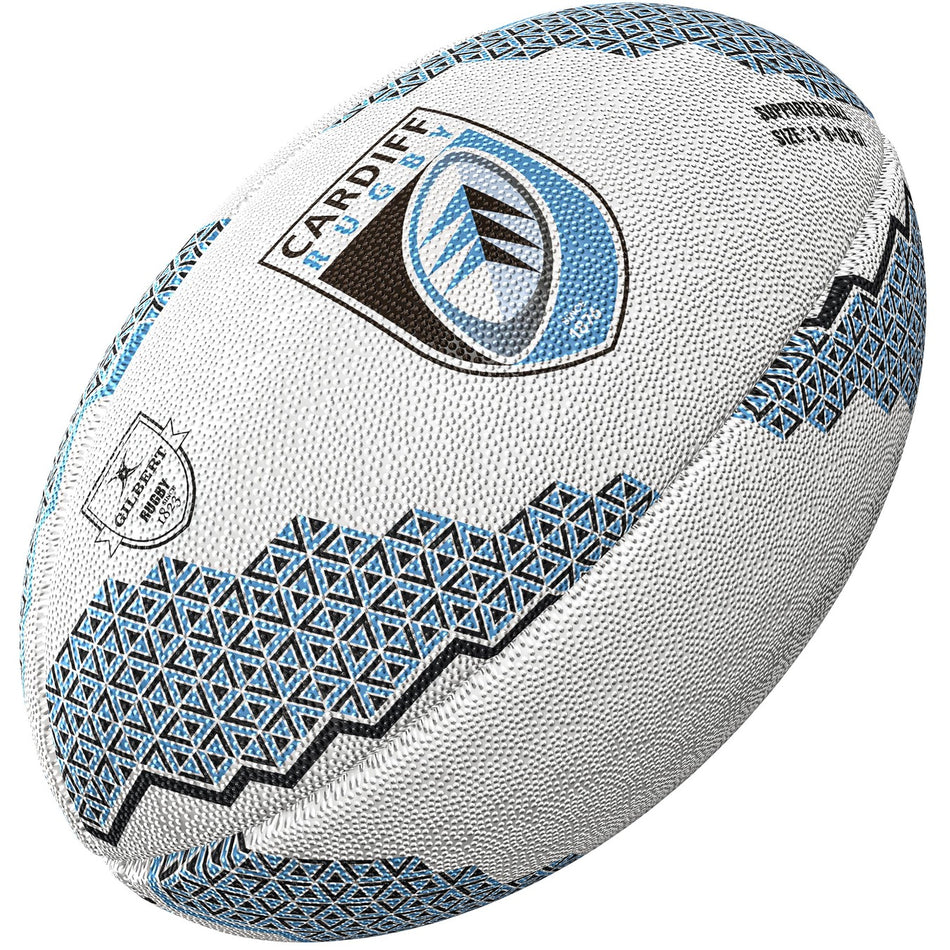 The Gilbert Cardiff Supporters Rugby Ball by Gilbert, featuring the Cardiff Rugby logo and geometric patterns in white and blue, is displayed against a white background—ideal memorabilia for United Rugby Championship fans.