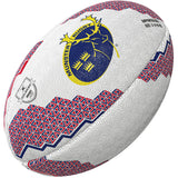 The Gilbert Munster Supporters Rugby Ball by Gilbert features red and blue geometric patterns, a textured white surface, the Munster Rugby stag logo on one side, and a small silver badge—perfect memorabilia for any fan.
