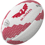 The Gilbert Scarlets Supporters Rugby Ball features a white base, red geometric patterns, a red dragon graphic, and "Scarlets" printed on the side—ideal for any Scarlets fan or to mark the United Rugby Championship.